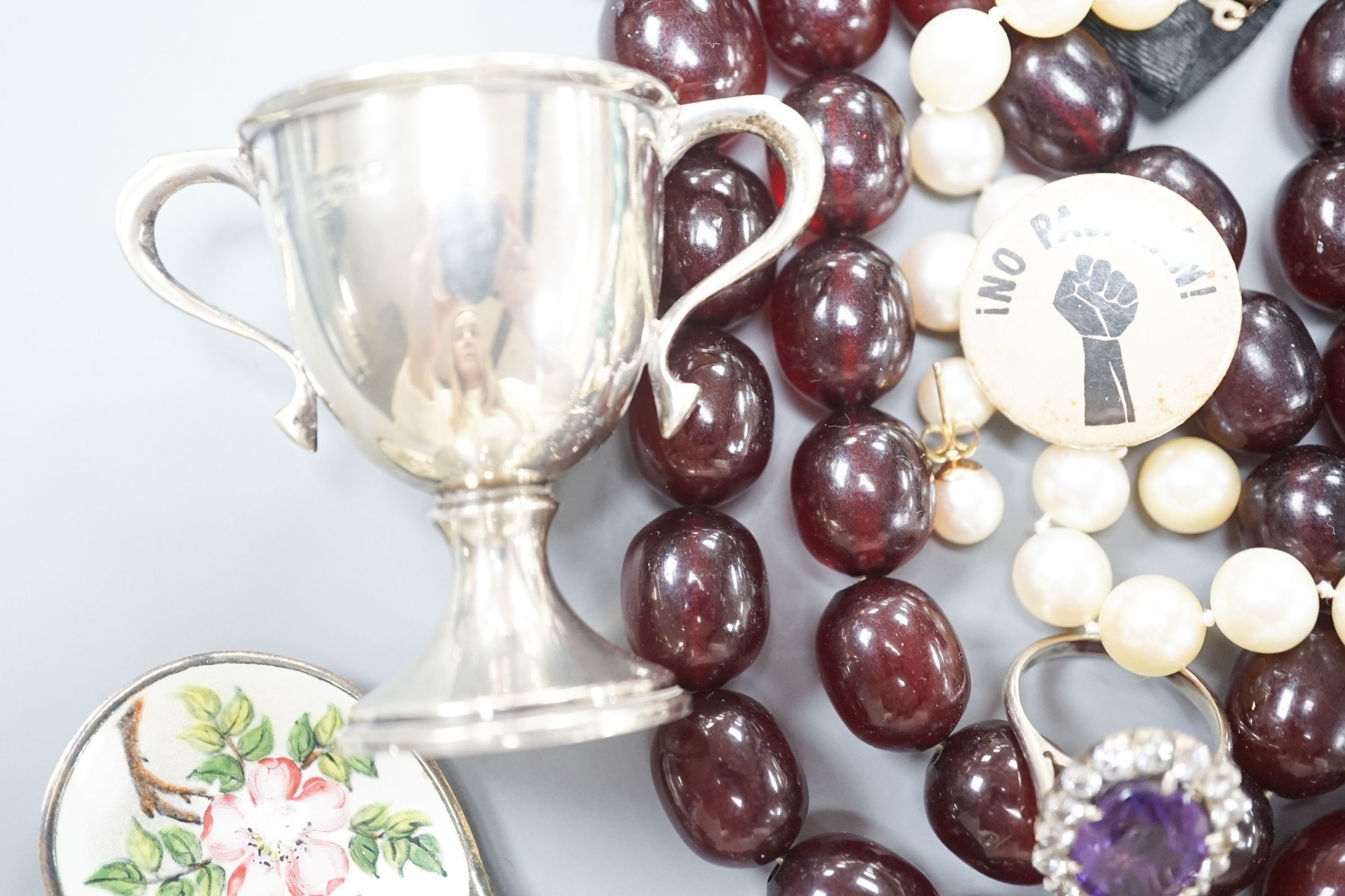 Assorted costume jewellery, etc. including small silver trophy cup, simulated amber necklace and git metal locket.